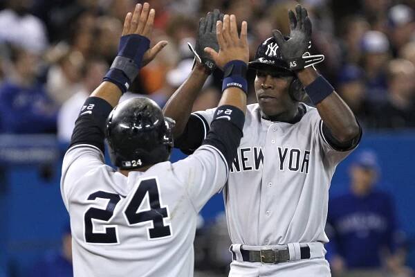 Alfonso Soriano (right) gets a high-five from Robinson Cano after they both score on Vernon Wells' double in the eighth inning that gave the Yankees the lead.