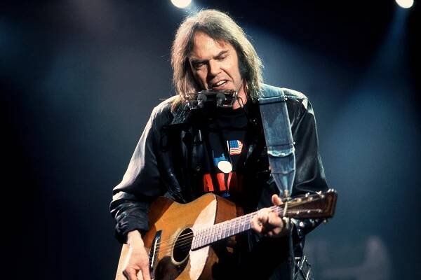 Canadian Folk and Rock musician Neil Young plays guitar as he performs onstage during the Farm Aid benefit concert, Indianapolis, Indiana, April 7, 1990. (Photo by Paul Natkin/Getty Images)