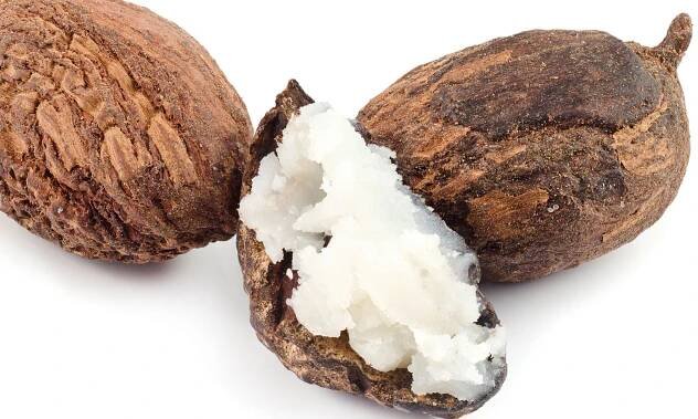 Drei Shea-Nüsse, eine von ihnen ist geöffnet und man sieht die weiße Shea-Butter darin.