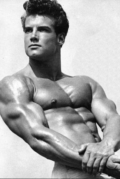 Photo of the bodybuilder Steve Reeves, showing his fully developed chest from doing the bench press.