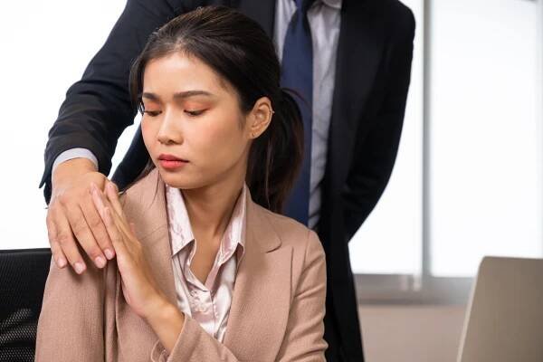 Selective focus at women face. Young beautiful women office worker sitting with hand of men touch her body. Sexual harassment in workplace, discrimination of women concept.