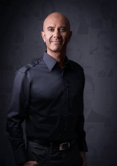a bald man in a black shirt and jeans posing for a photo with his hands on his hips