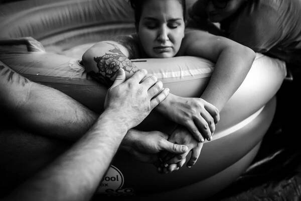 hands support mother through labor at home in Fort Worth
