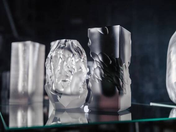 three glass vases sitting on top of a glass table next to each other in front of a black wall