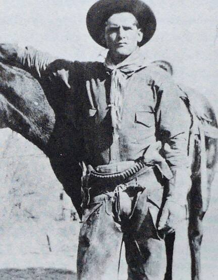 Young Butch Cassidy standing beside a horse. 