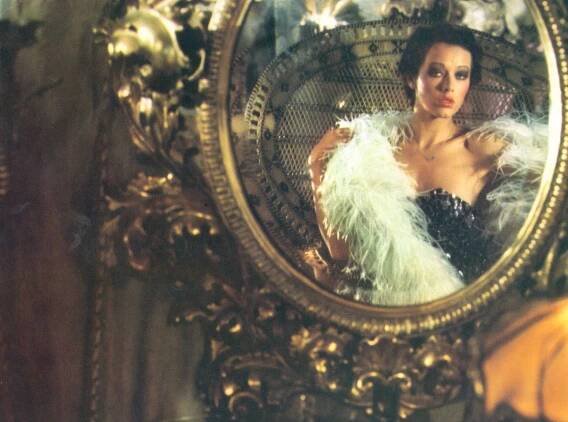 a woman in a feathered dress is reflected in a mirror