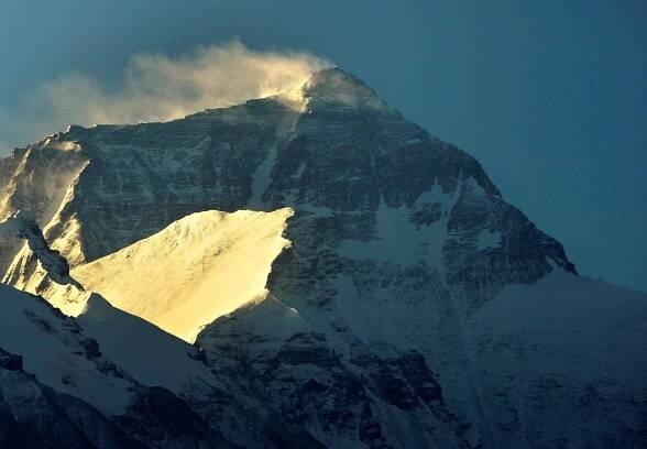Wind blows snow off the summit at sunrise of the world's highest mountain Mount Everest, also known as Qomolangma, in the Tibet Autonomous Region