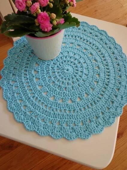 a potted plant sitting on top of a table next to a crochet doily