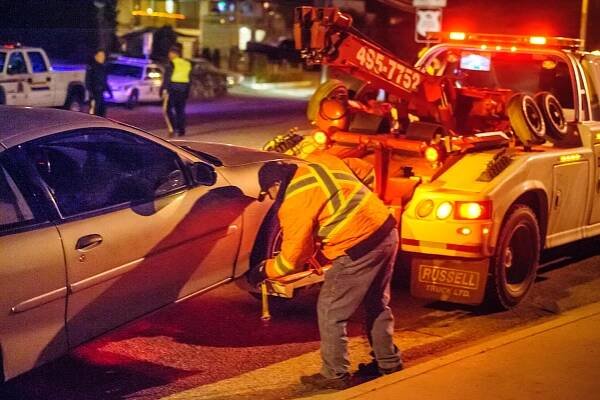 Tow truck operator Laurence Usher of Usher's Towing hooks up the vehicle of a woman who received a 90-day driving suspension. Her vehicle will be impounded for 30 days. (Richard McGuire Photo)