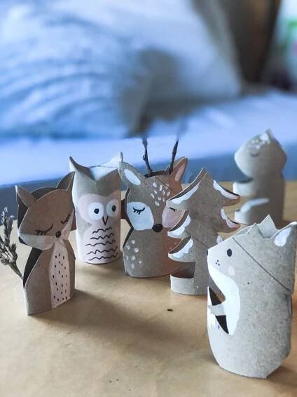 some paper animals are sitting on a table next to a blue bed and pillows in the background