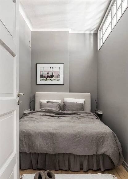 a bed sitting in a bedroom next to a white door with two pictures on the wall