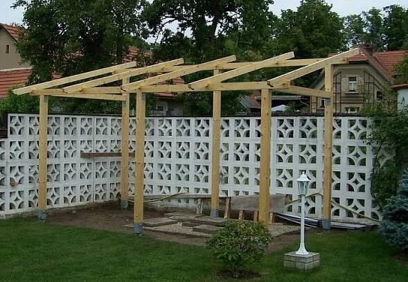 a wooden pergolan sitting in the middle of a yard next to a fence