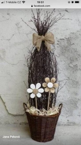 a basket filled with fake flowers next to a white wall and a brown bow on the top