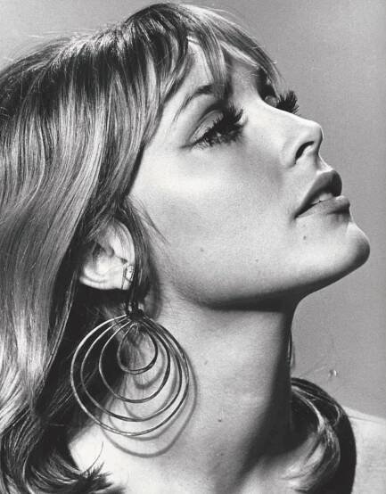 a black and white photo of a woman with large hoops on her earring