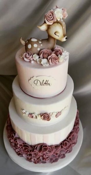 a three tiered cake decorated with flowers and a deer figurine on top