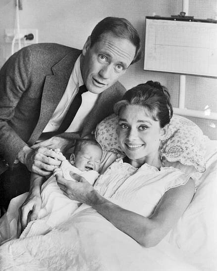 A man and a woman posing for a photo with their newborn baby in 1960