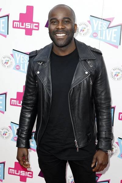 a man in a black leather jacket stands in front of a sign that says yes live