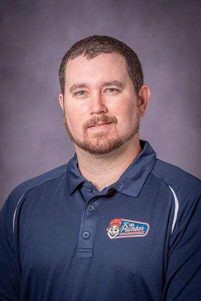 A man with a beard is wearing a blue polo shirt.