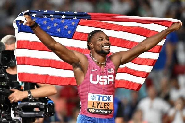 Noah Lyles, winner of the men's 200m final at the World Athletics Championships, celebrates with an American flag.