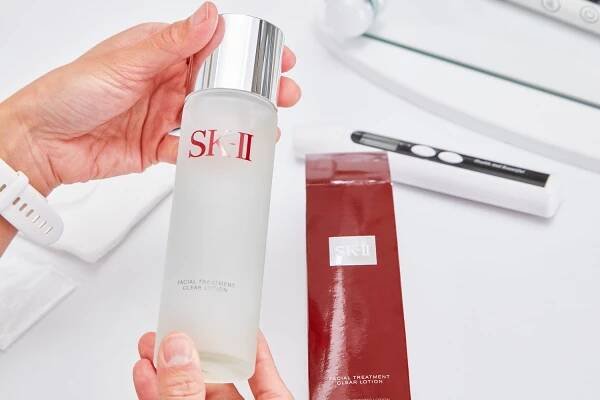 Hand holding the SK-II Facial Treatment Clear Lotion Toner next to its retailer box