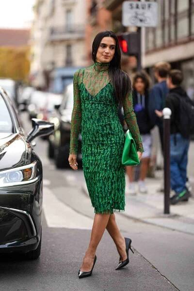Person wearing a cocktail dress with sheer green overlay, heels, and a purse