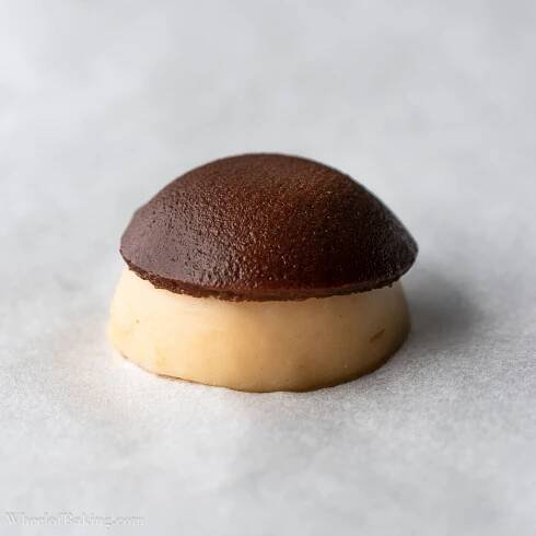 Chocolate craquelin has started to melt and wrap around choux pastry.