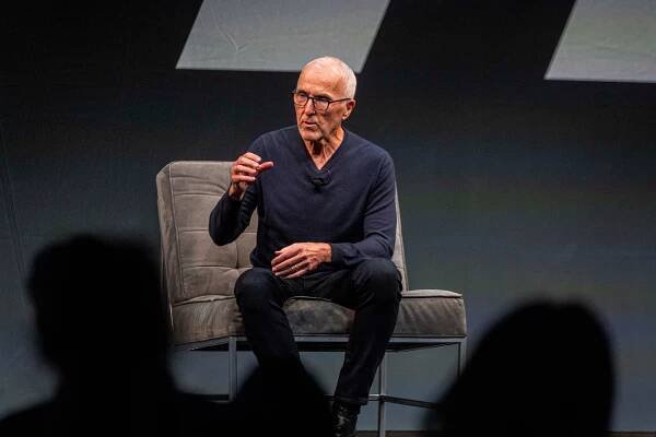 Frank McCourt, sitting on a gray upholstered chair, speaking onstage.