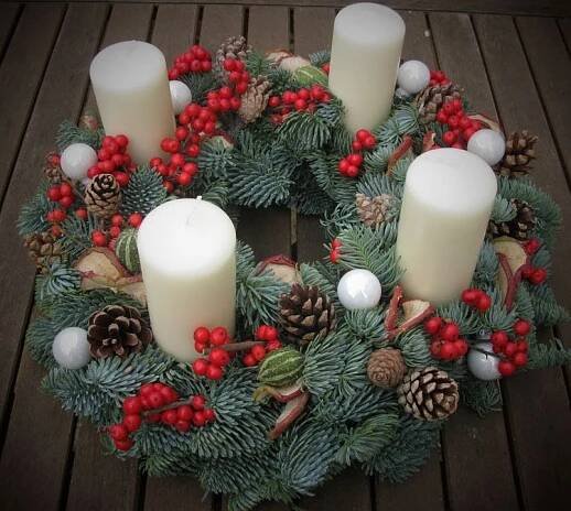 a christmas wreath with candles and pine cones