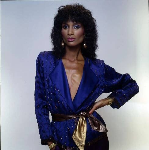 Beverly Johnson wearing an embellished navy blue blazer with a gold belt tied at her waist