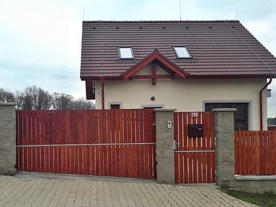 Zakázková výroba posuvné brána na kolejnici ve svahu. Výplň svislá modřínová prkna. Realizace v Mukařově. 