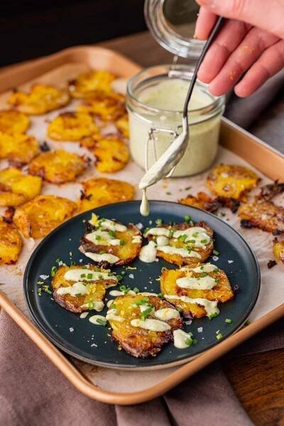 drizzling lemon chive dressing over duck fat smashed potatoes.