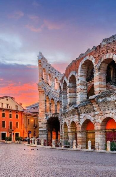the sun is setting over an old roman amphith in italy, with people walking around