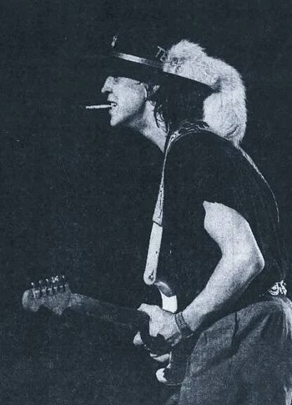 an old photo of a man with a hat on his head and holding a guitar