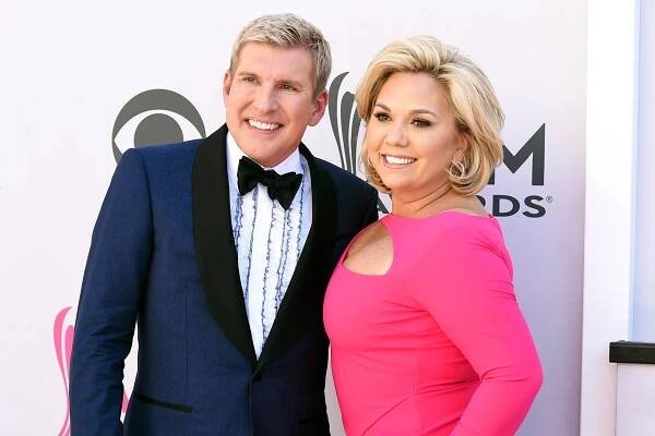 A man in a blue tuxedo poses with a woman in a pink dress.