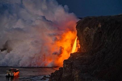 a smokey and bright lava flow into the ocean at night