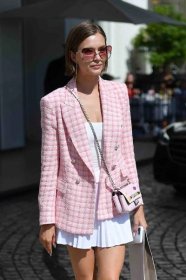 A woman shows how to style a tennis skirt with a pink tweed jacket.