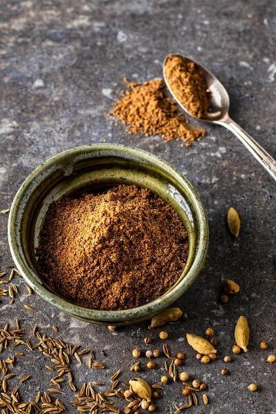 a bowl filled with spices next to two spoons