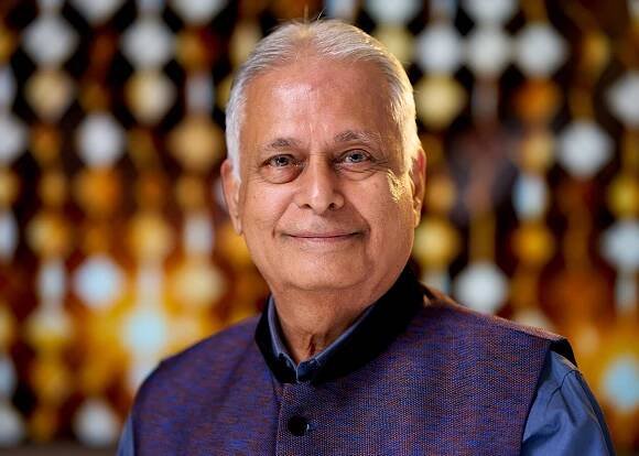 Portrait of person in navy traditional attire against golden bokeh background.