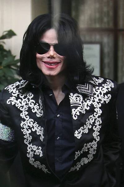the man is dressed in black and white with sunglasses on his head, smiling at the camera