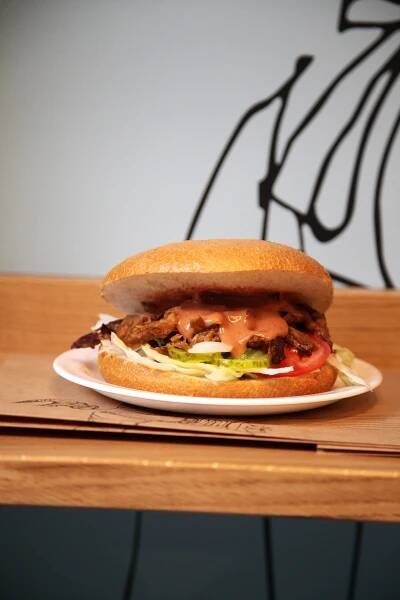 Eine Semmel mit Ochsenfleisch belegt auf einem Teller auf einem Holzbrett