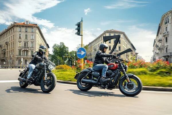 Two riders on Keeway V302 C are passing by a city garden