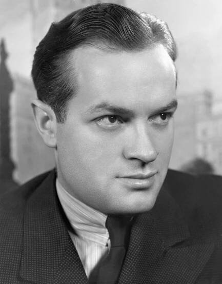 Man in a suit with slicked-back hair poses for a formal portrait