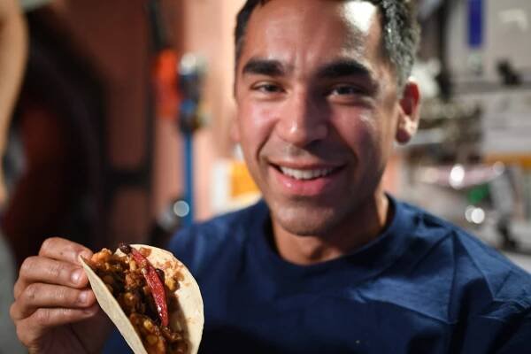 NASA astronaut and Expedition 66 Flight Engineer Raja Chari holds a taco made with freshly harvested peppers grown aboard the International Space Station as part of the Plant Habitat-04 (PH-04) experiment.