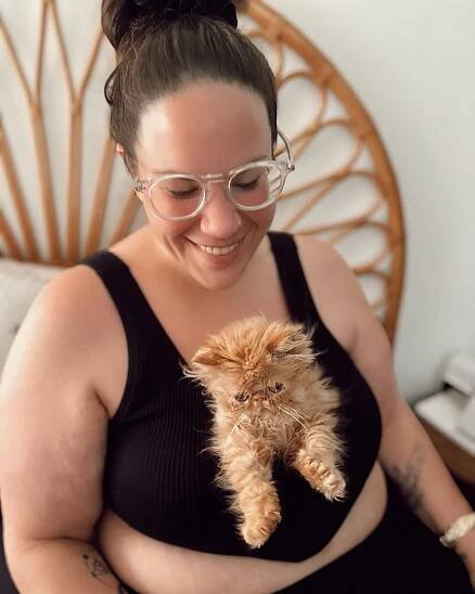 Woman holding an orange kitten.