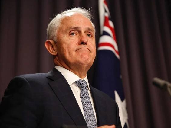 Malcolm Turnbull frowns during a press confernce, standing at a microphone in front of an Australian flag.