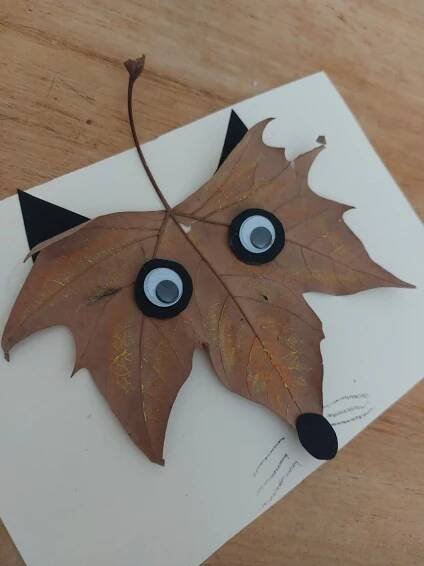 a leaf with googly eyes on it sitting on top of a piece of paper