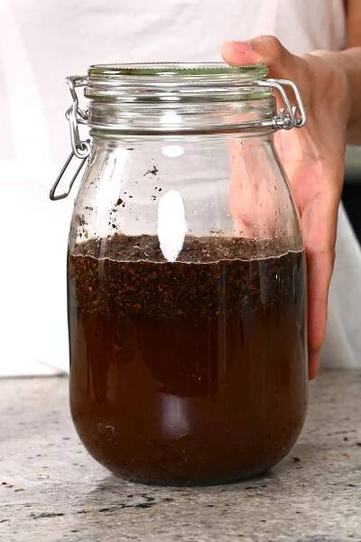 Mixing water and ground coffee in a large jar