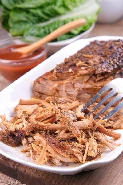 Homemade keto pork cooked in slow cooker getting shredded with a fork.