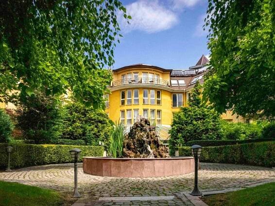 Maison Sofia - Mgallery Exteriér fotografie The photo shows a beautiful, sunny courtyard with a grand, yellow building as its focal point. The building has multiple floors with numerous windows, some of which have balconies. The architecture appears to be classic European, with arched windows 