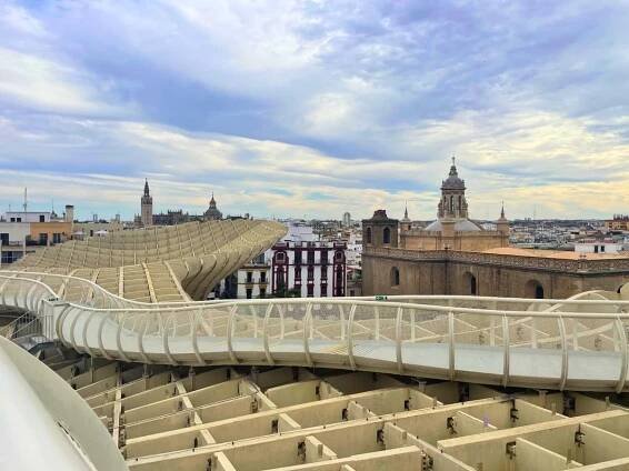 Elevated view of the Metropol Parasol walkway curving through the skyline with historic buildings in the background in Seville's Setas de Sevilla